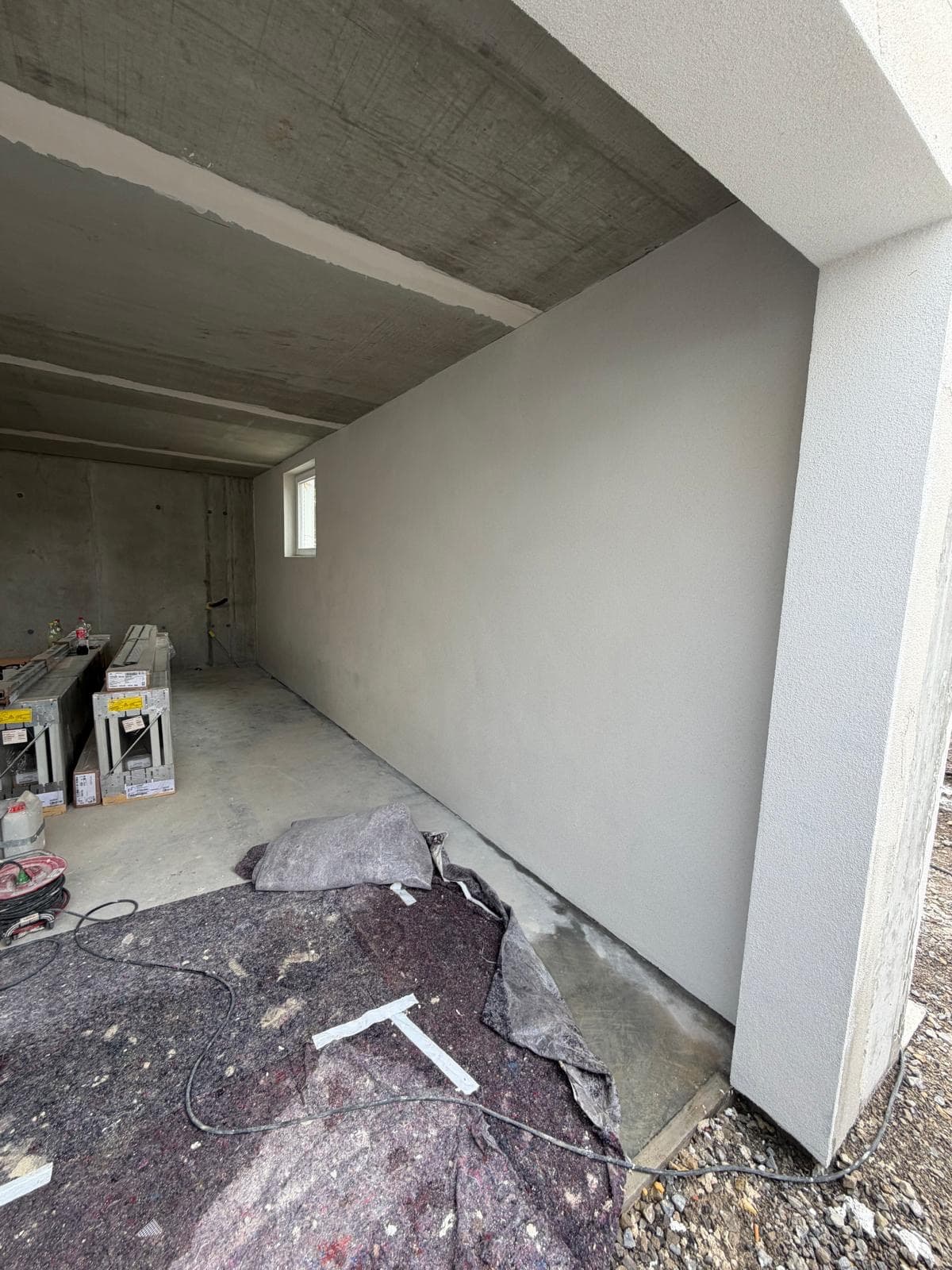 Frisch verputzte, hellgraue Innenwand in einer Garage im Rohbau