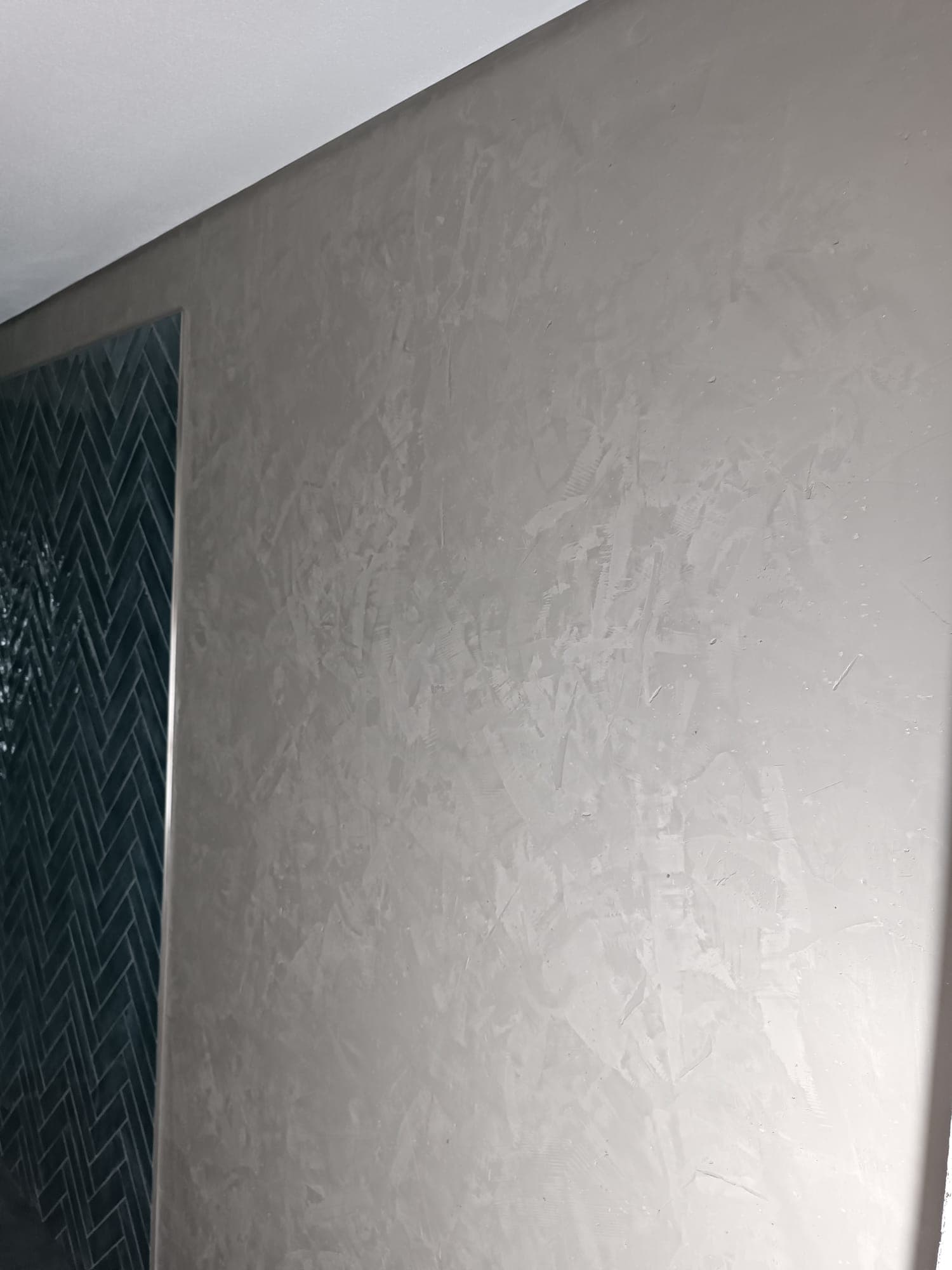 Wohnzimmerwand mit changierender Spachteltechnik neben Fischgrätparkett