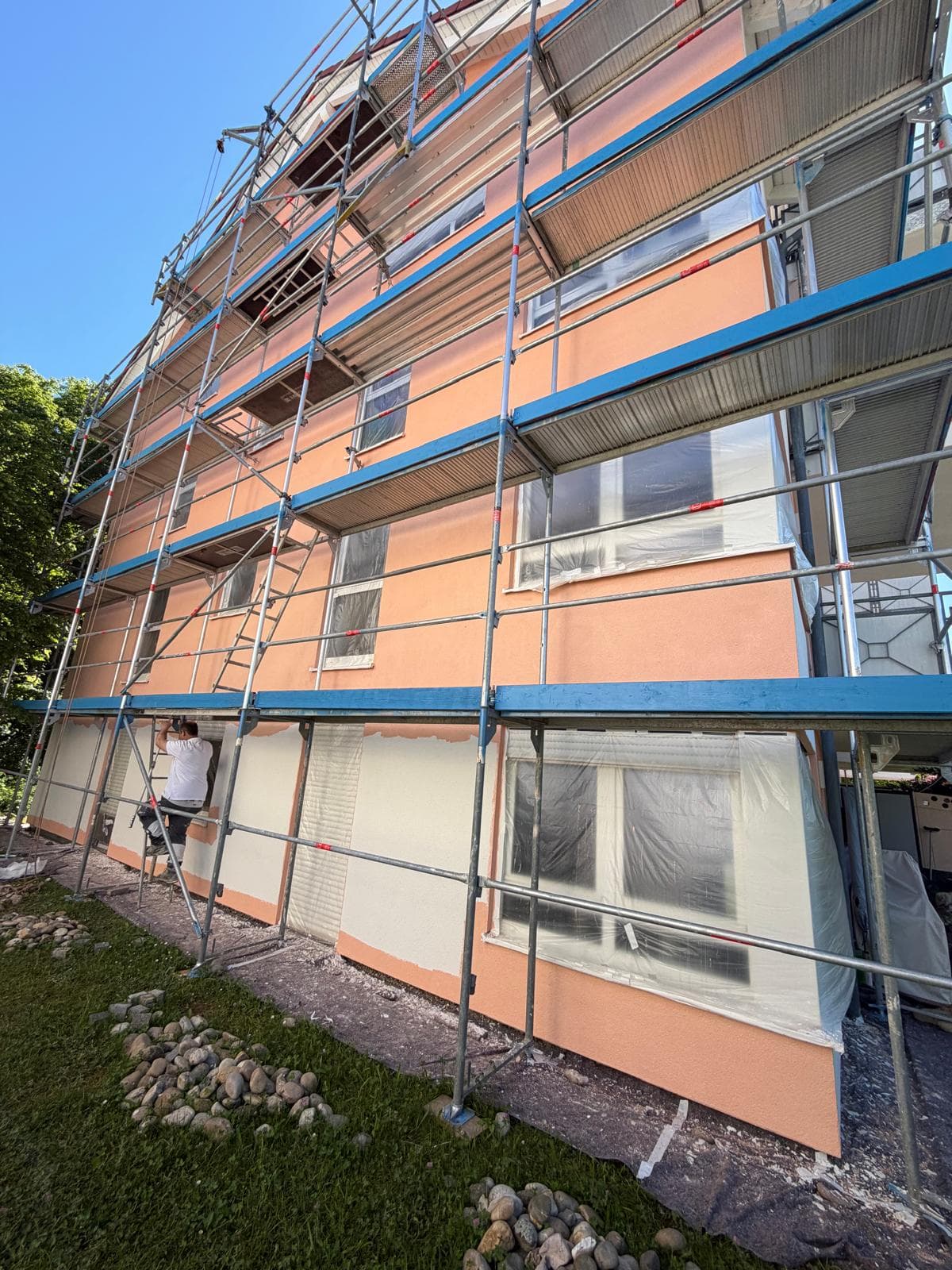 Wärmedämmverbundsystem mit terrakottafarbenem Oberputz an einem Mehrfamilienhaus