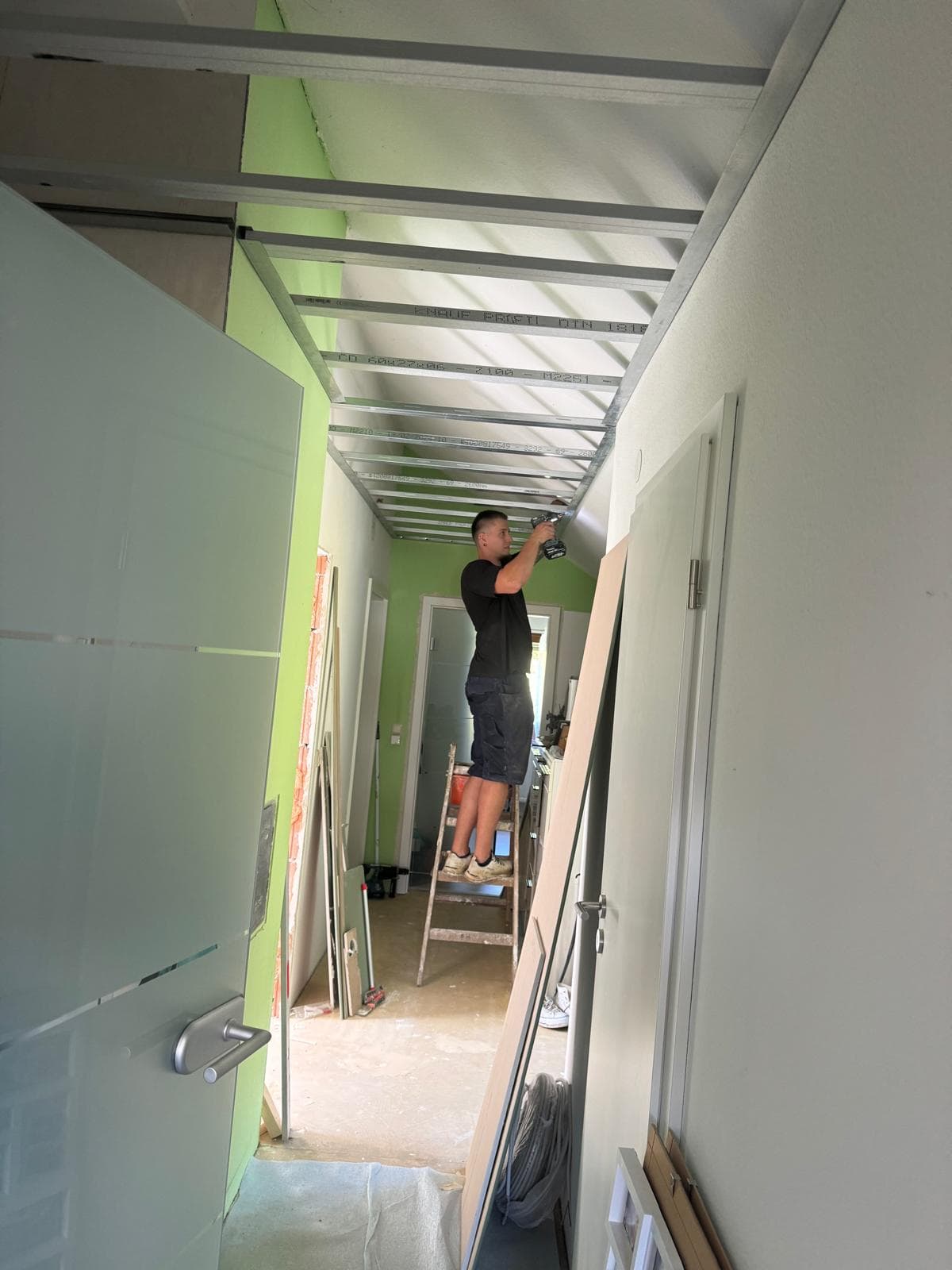 Handwerker montiert eine abgehängte Akustikdecke in einem Fluraufbau